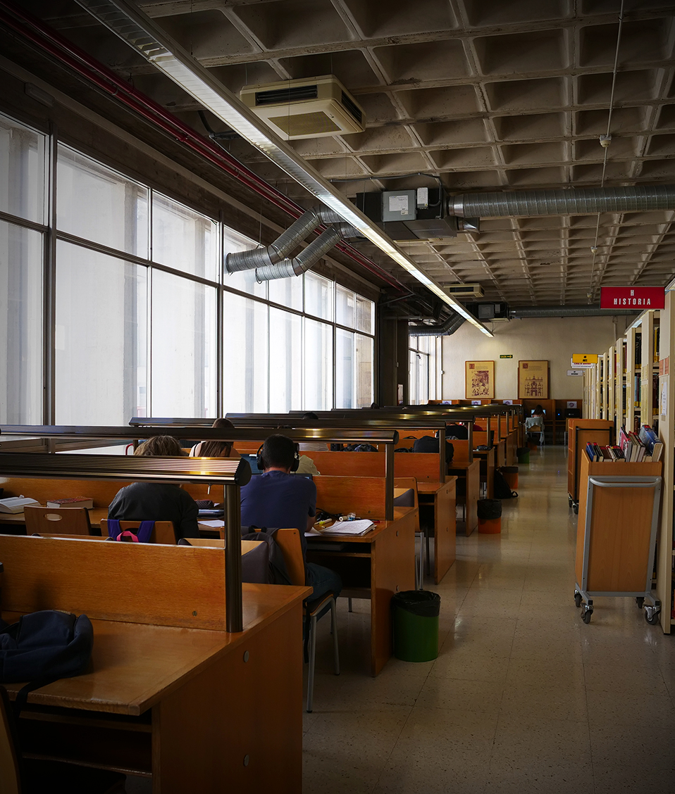 Biblioteca de la Facultad de Filosofía y Letras de la Universidad de Granada donde se ven estanterías con libros y estudiantes haciendo uso de las mesas de estudio