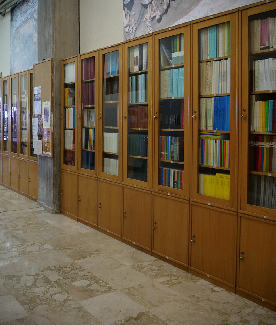 Imagen de diversos estantes con libros y puestos de estudio situados en la biblioteca de la Facultad de Filosofía y Letras